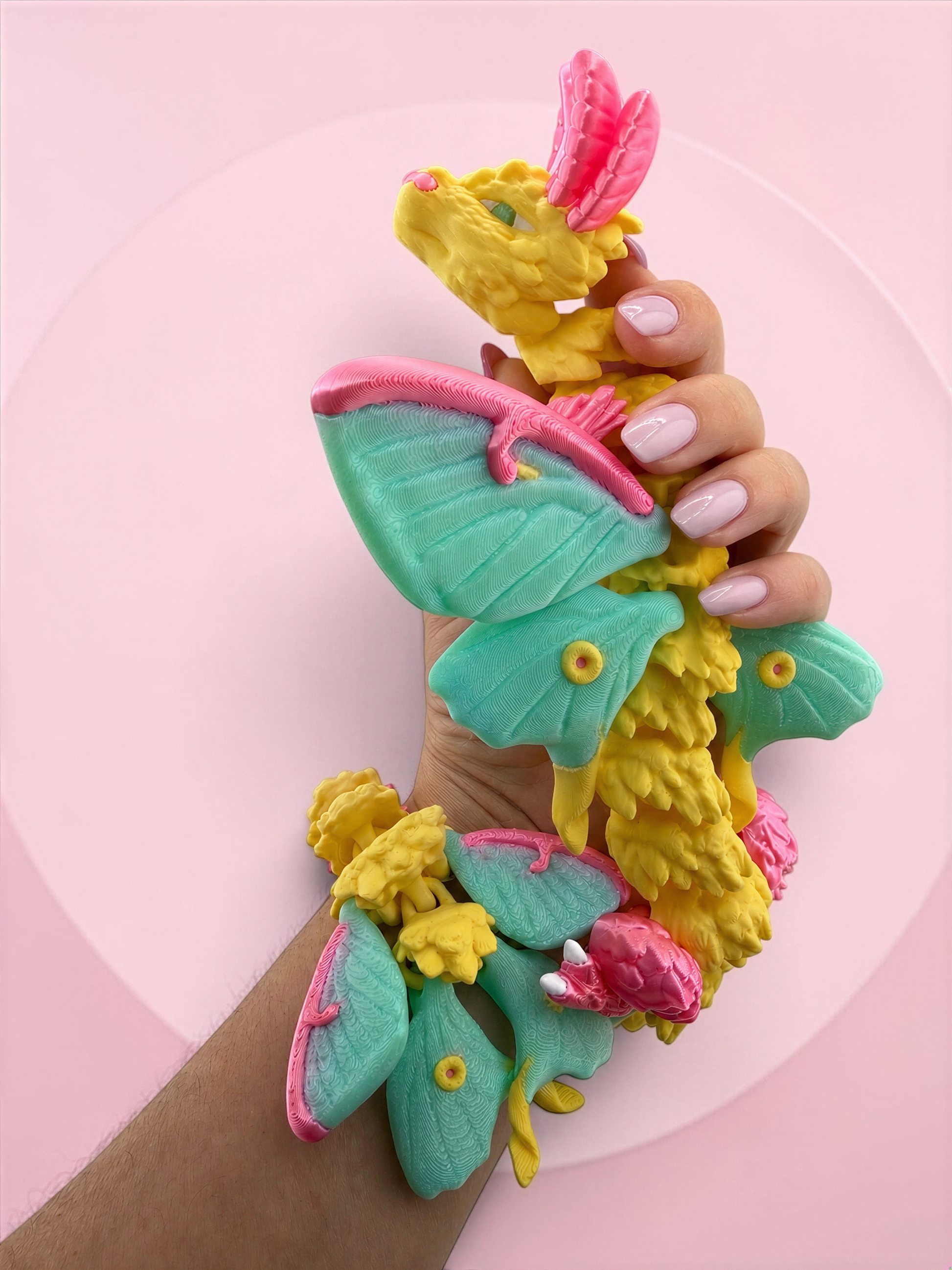 A hand holding a colorful, whimsical toy resembling a dragon or mythical creature with wings and other fantastical elements.