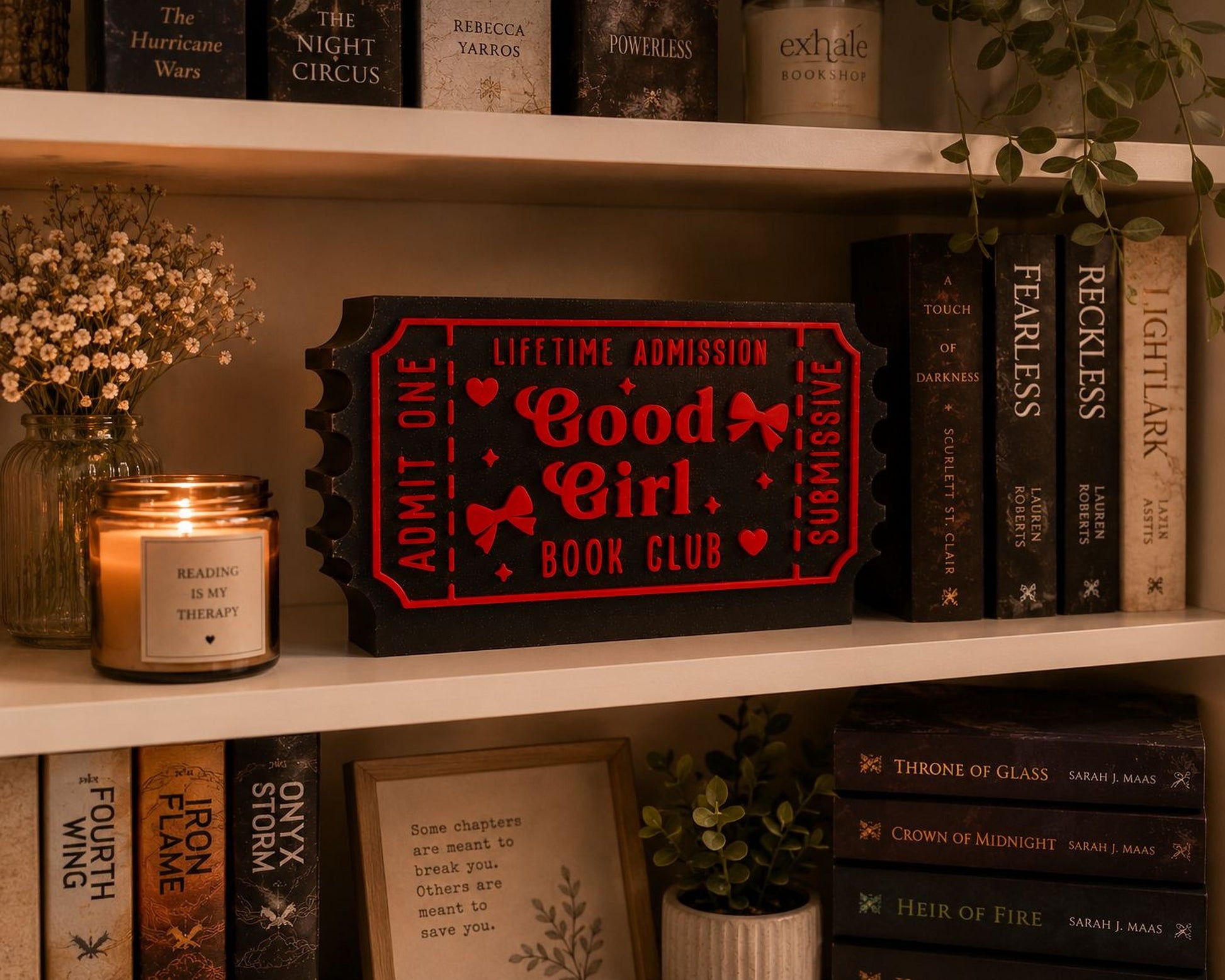a bookshelf with various books, a candle, and a framed picture. The bookshelf has a mix of hardcover and paperback books, and there is a red ticket-shaped object on the shelf.