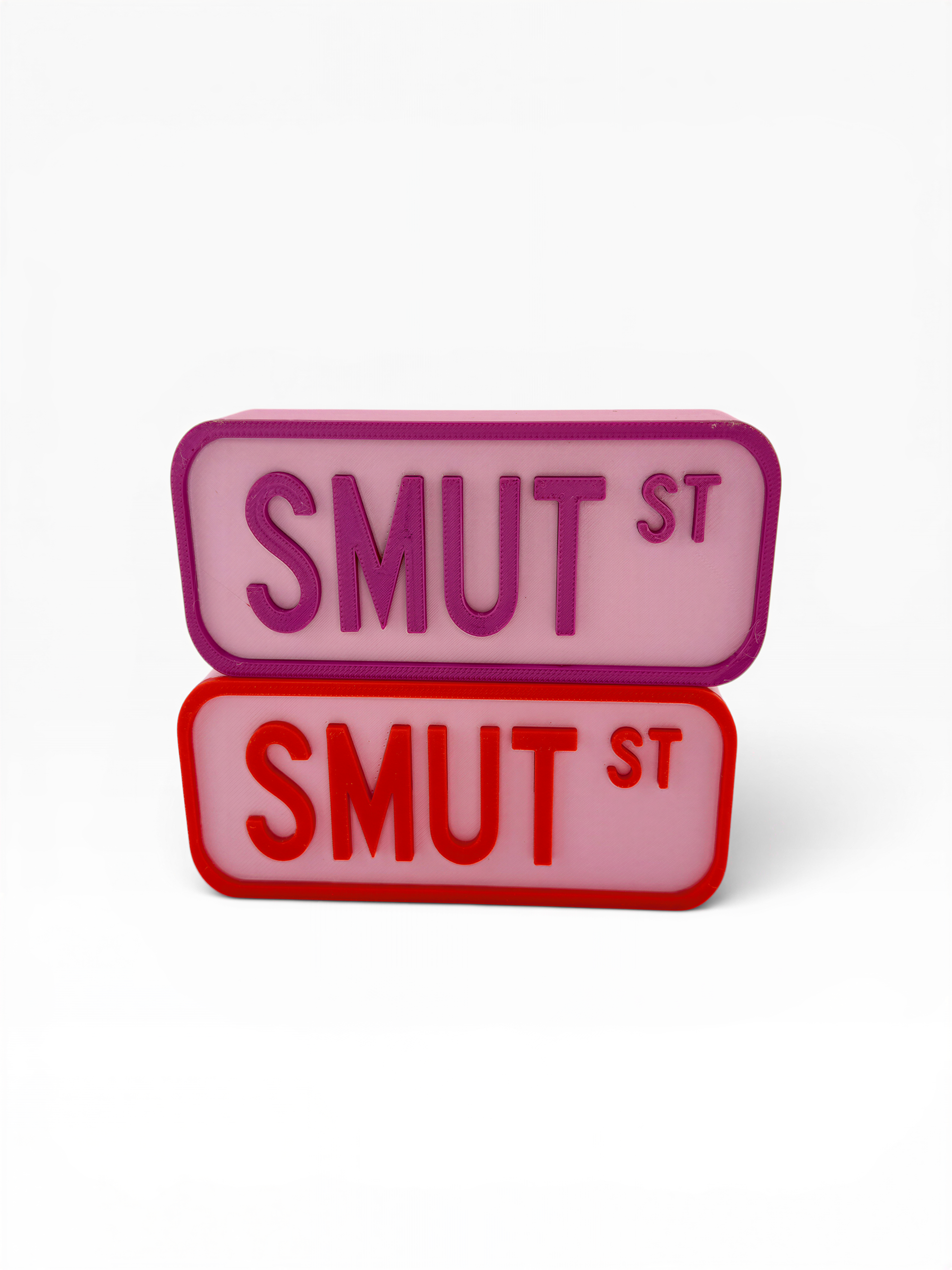 two rectangular signs with the text "SMUT ST" in different colors - one in pink and one in red.