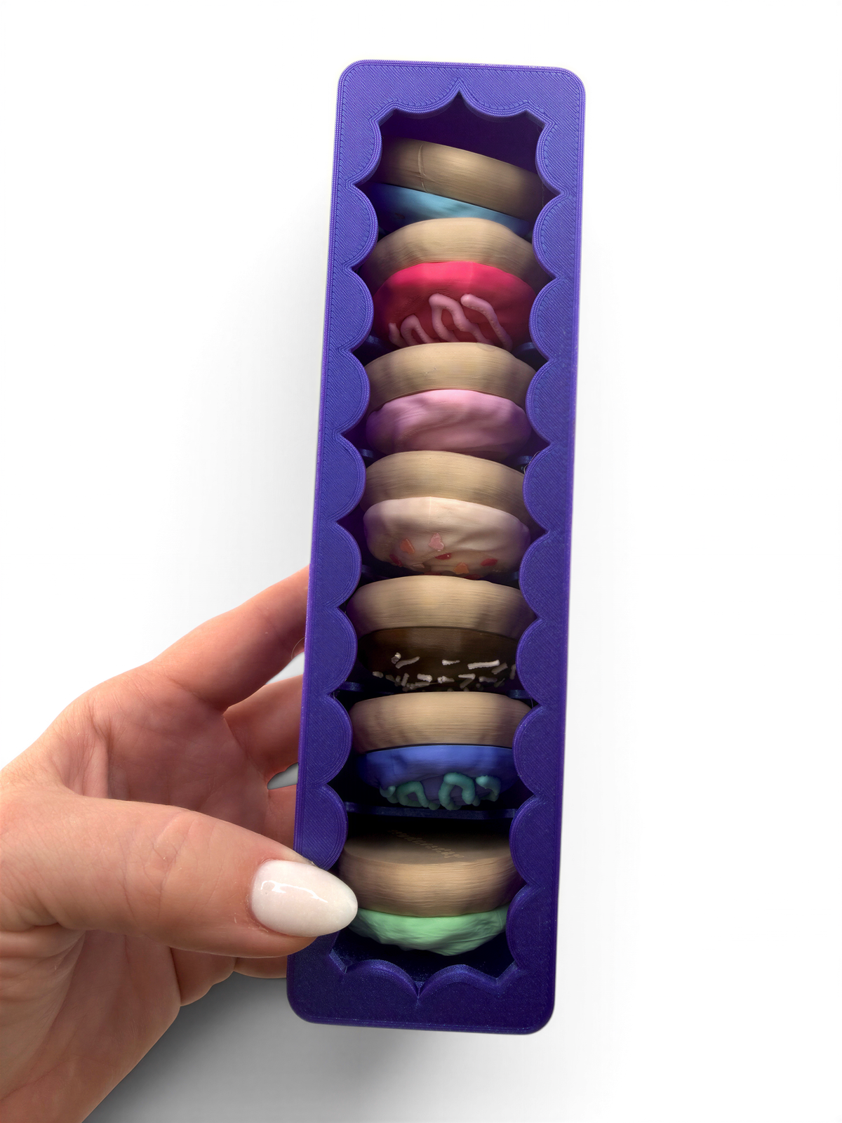 A hand holding a purple container with a row of colorful donuts inside.