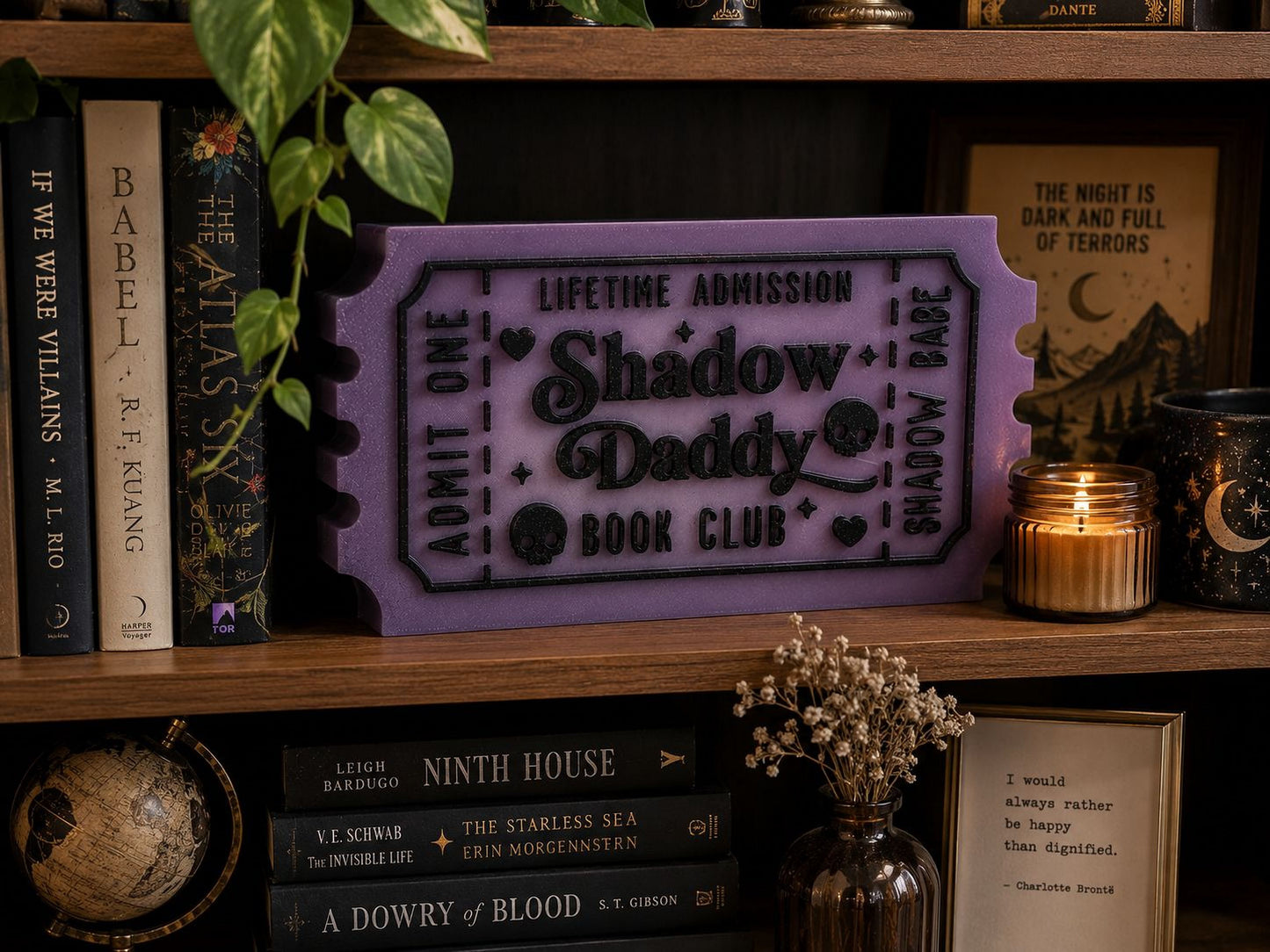 a bookshelf with various books, a purple ticket-shaped object, and some decorative items such as a candle and a vase.