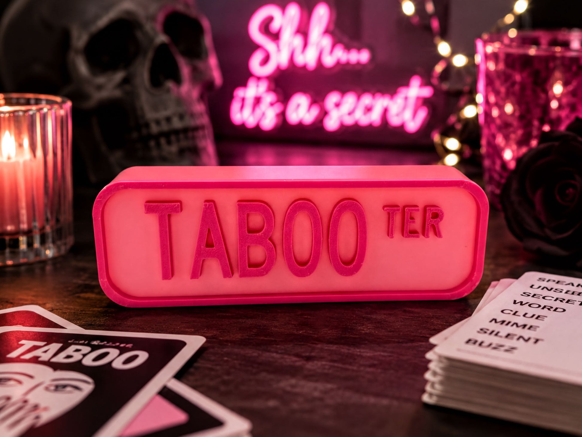 a pink Taboo sign on a table, surrounded by various objects such as a candle, a skull, and a stack of cards.