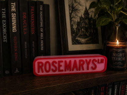 a bookshelf with a collection of horror movies, including "The Shining", "Dracula", "The Haunting of Hill House", "The Exorcist", and "Night Terror". There is also a red sign with the word "ROSEMARYS" in the foreground, and a candle is visible in the background.