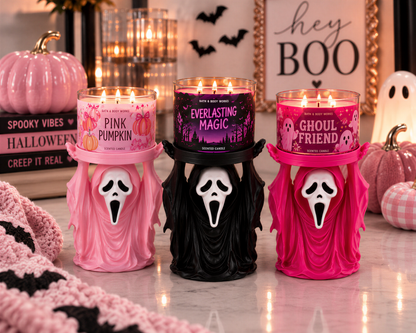 three Halloween-themed candles with spooky faces, placed on a table with other Halloween decorations.