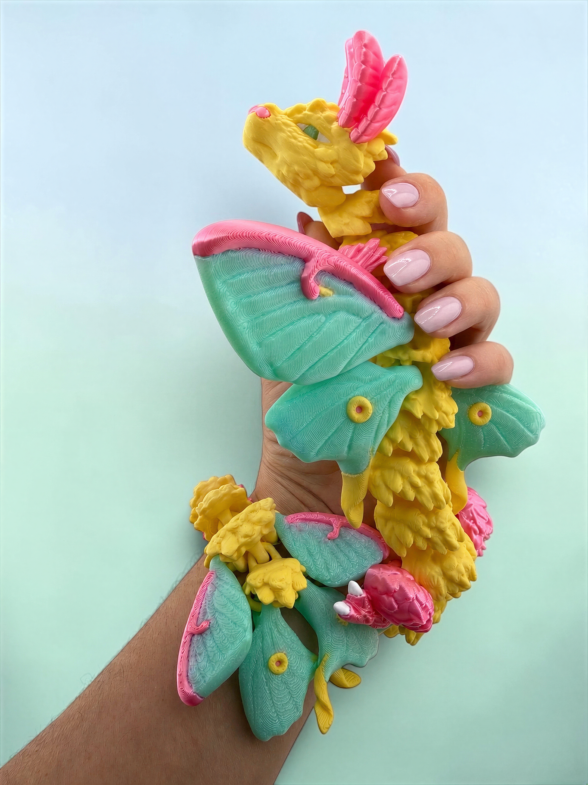 A hand holding a colorful, whimsical toy resembling a dragon or sea creature with vibrant green, pink, and yellow colors.