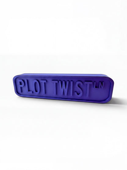 A purple rectangular object with the text "PLOT TWIST" embossed on it.