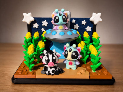 A whimsical diorama featuring three small, colorful toy animals in a space-themed setting, with stars and plants surrounding them.