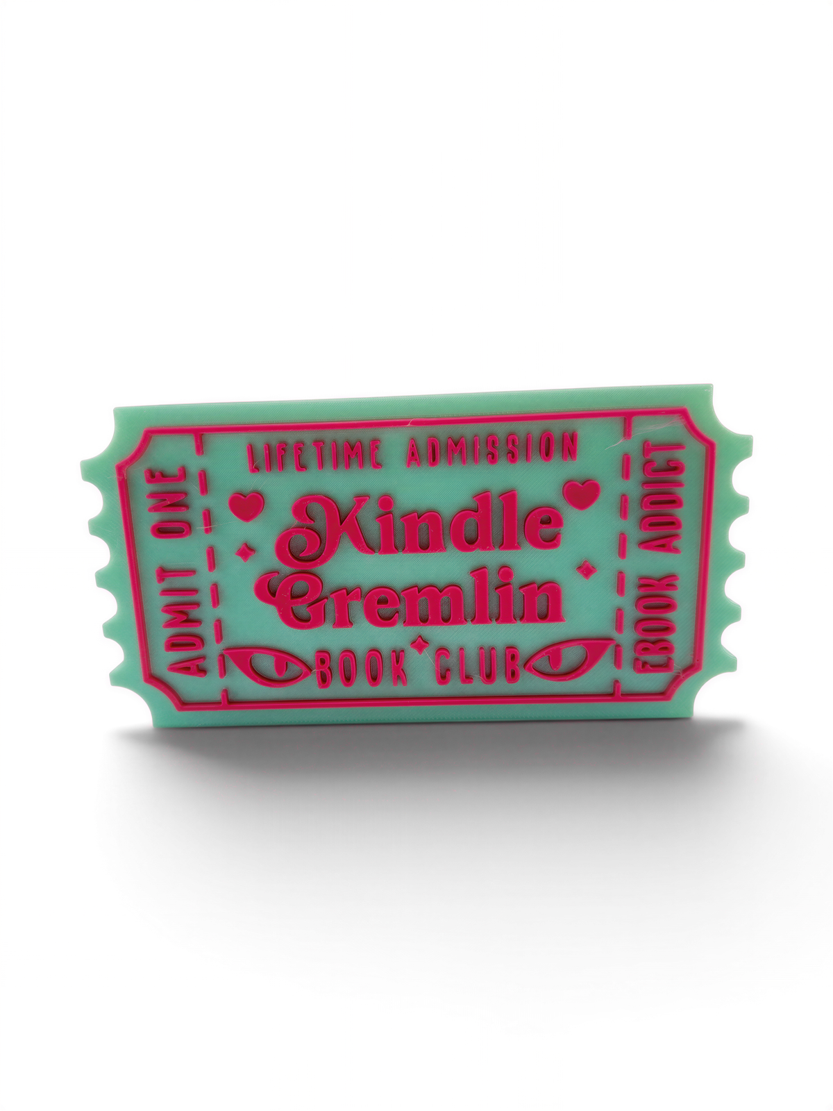A green and pink ticket-shaped object with text that reads "Lifetime Admission Kindle Cremlin Book Club".