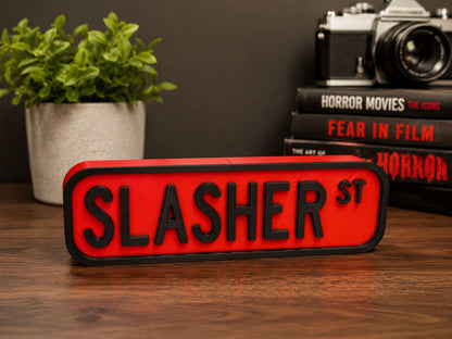 a red sign with the word "SLASHER ST" in bold black letters, placed on a wooden surface. In the background, there are several books and a camera, suggesting a scene related to the "Slasher" movie franchise.