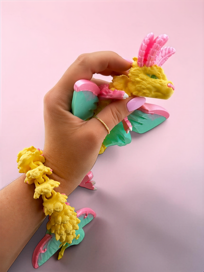 A hand is holding a colorful toy in a pink and green color scheme, with the toy's head and body visible.