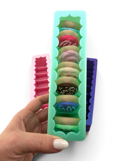 A hand holding a green container filled with colorful donuts.