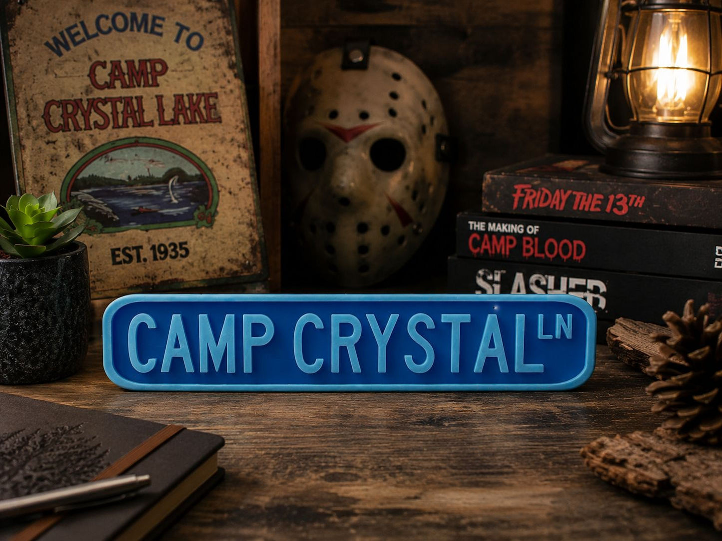 a sign that reads "CAMP CRYSTAL" in blue letters, surrounded by various items such as a mask, books, and a lantern.