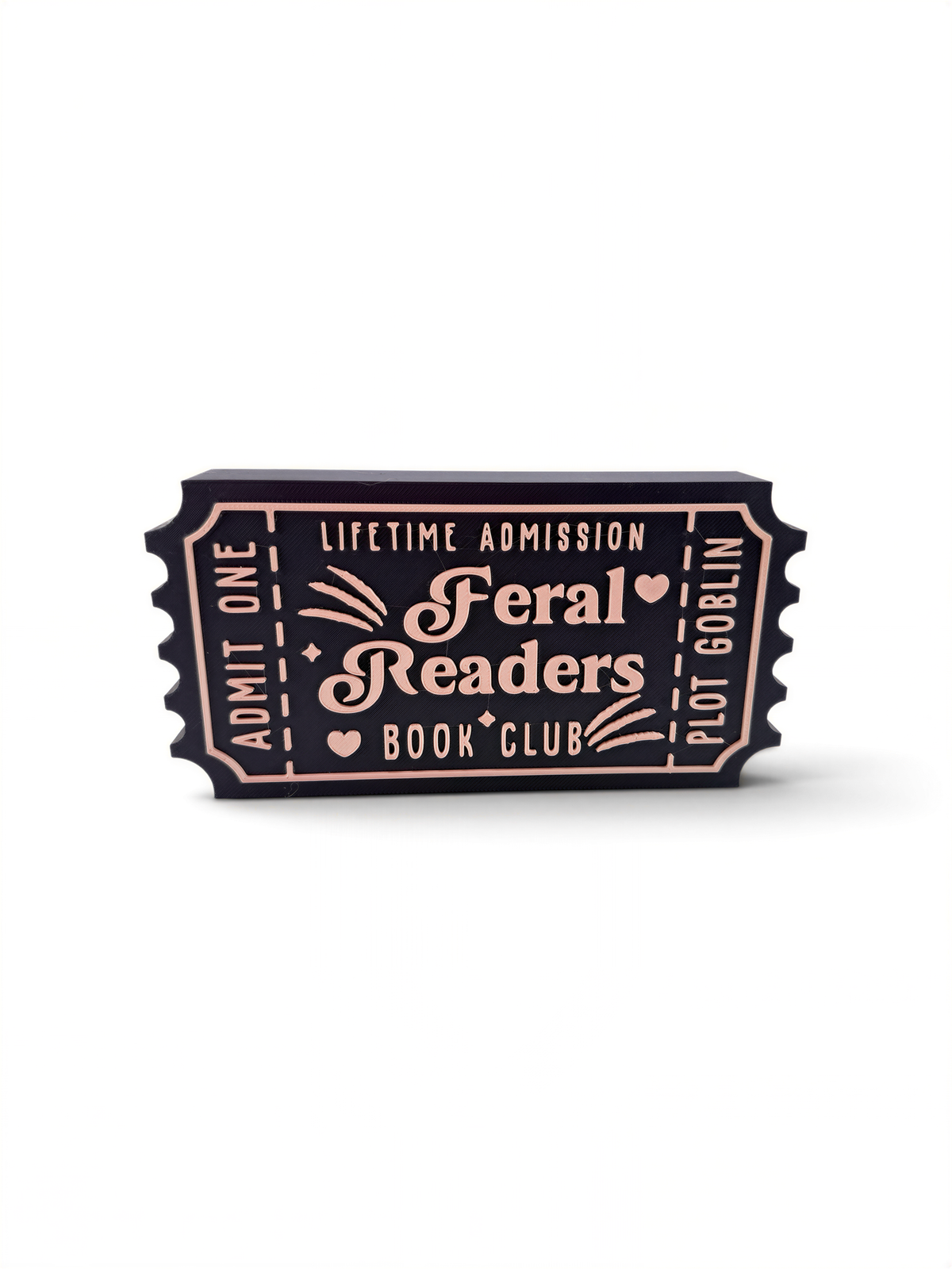 The image is a black and white photograph of a ticket-shaped object with text and decorative elements.