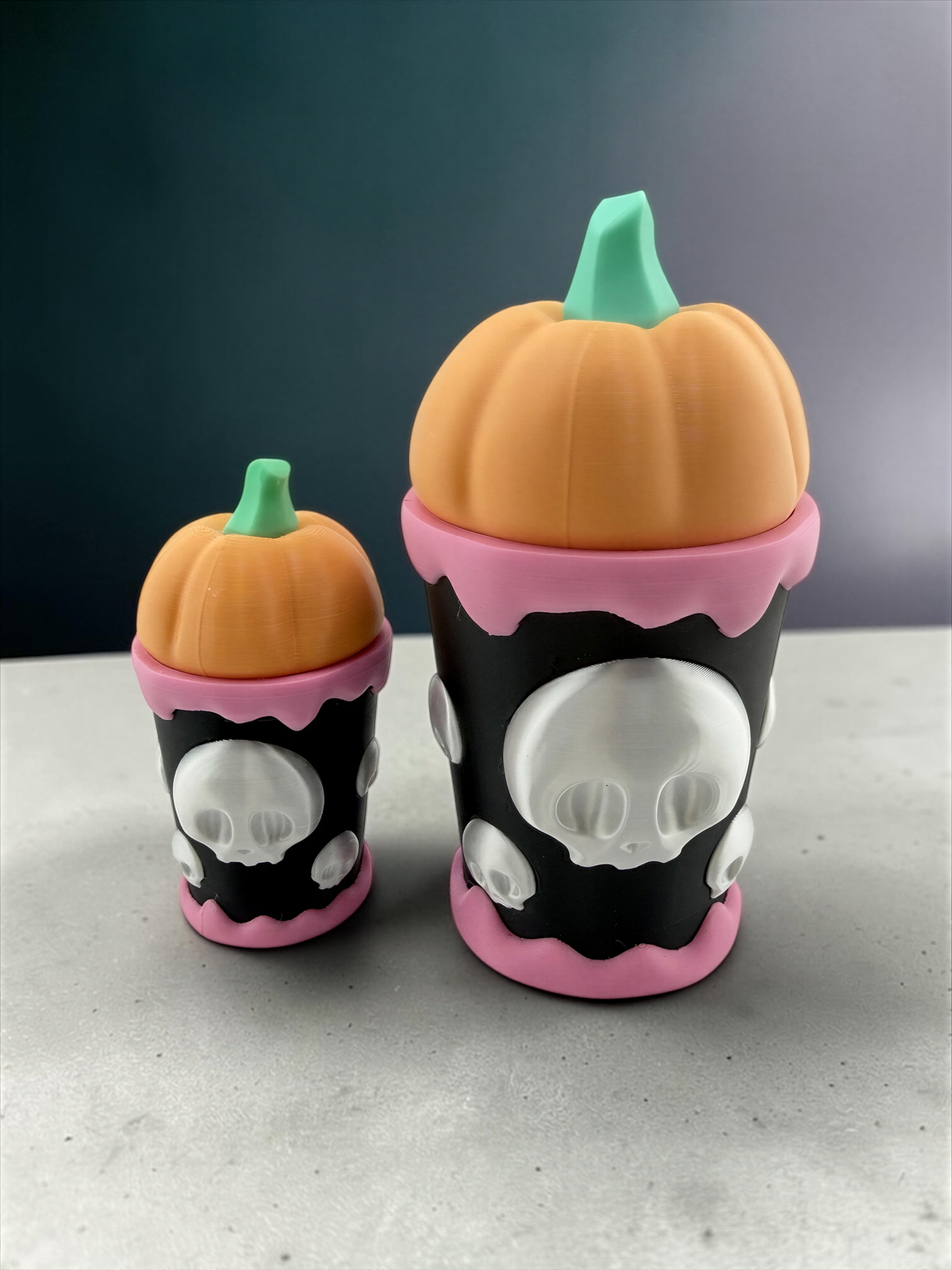 Two small, colorful pumpkin-shaped containers with skull designs on them, sitting on a surface.