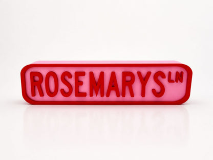A pink rectangular sign with the word "ROSEMARYS" in red letters.