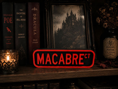a bookshelf with various books, a framed picture of a castle, and a red sign that says "MACABRE".