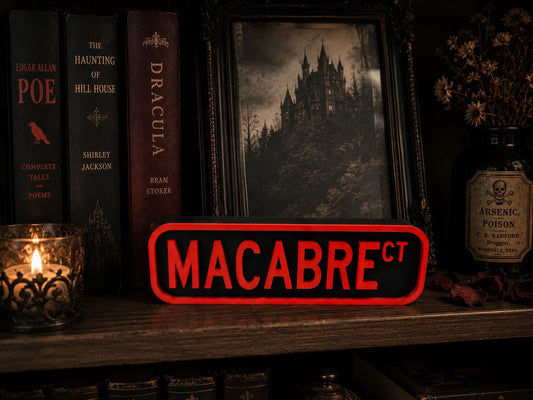 a bookshelf with various books, a framed picture of a castle, and a red sign that says "MACABRE".