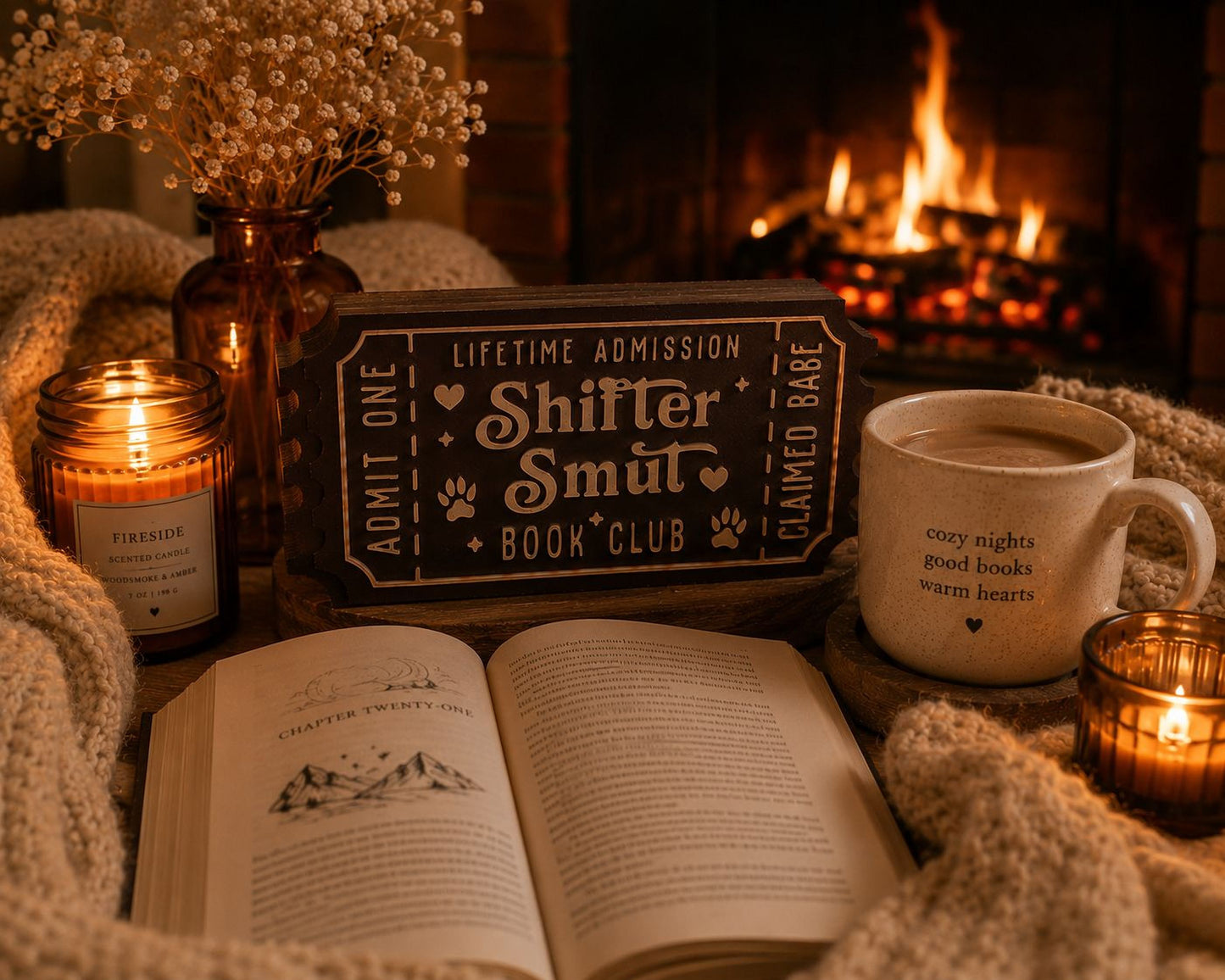a cozy scene with a lit candle, a mug of coffee, an open book, and a sign for the Shifter Smut Book Club.
