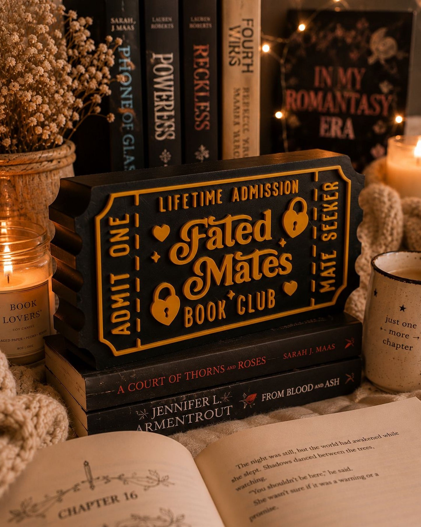 a collection of books, a candle, and a decorative ticket-like object, all arranged on a surface.