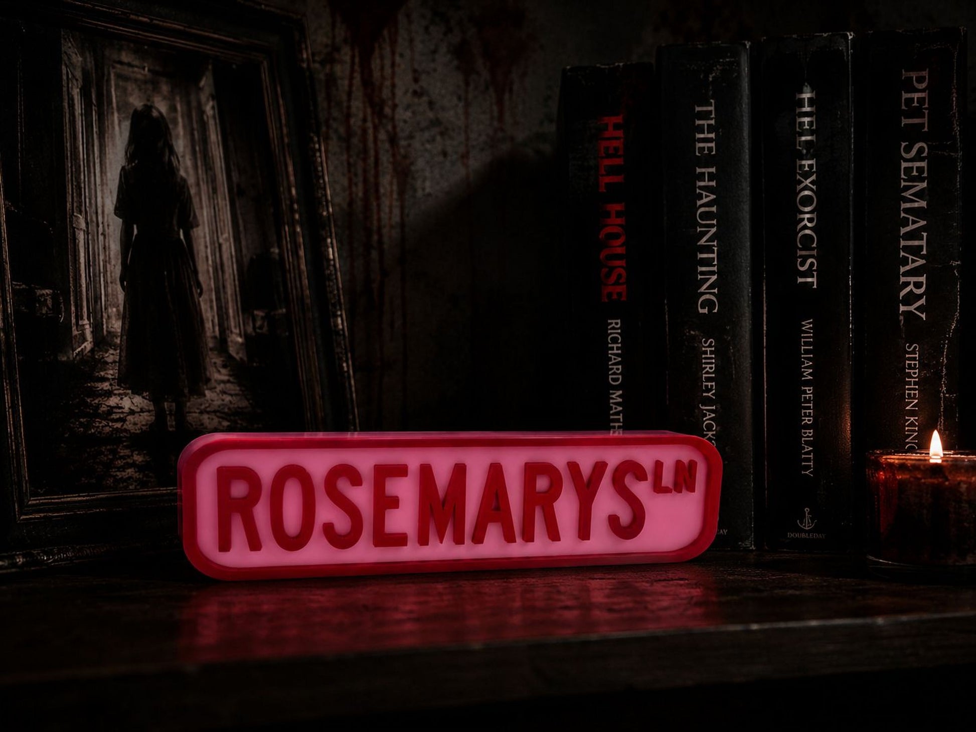 a dark, spooky scene with a red sign that reads "ROSEMARYS.LN" in the foreground, surrounded by a collection of horror books and a lit candle.