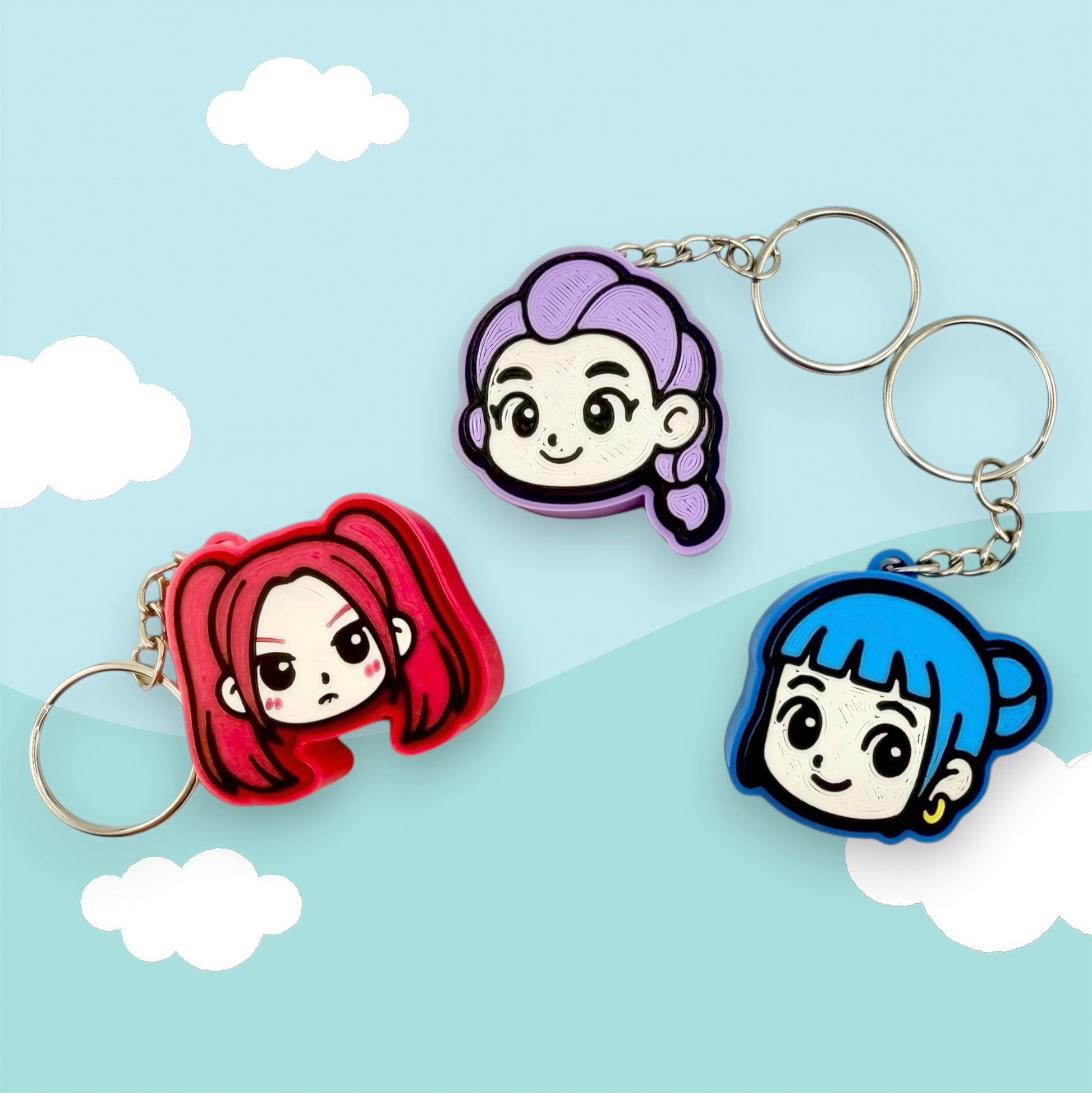 three keychains with cartoon-style female characters on them, set against a light blue sky with clouds.