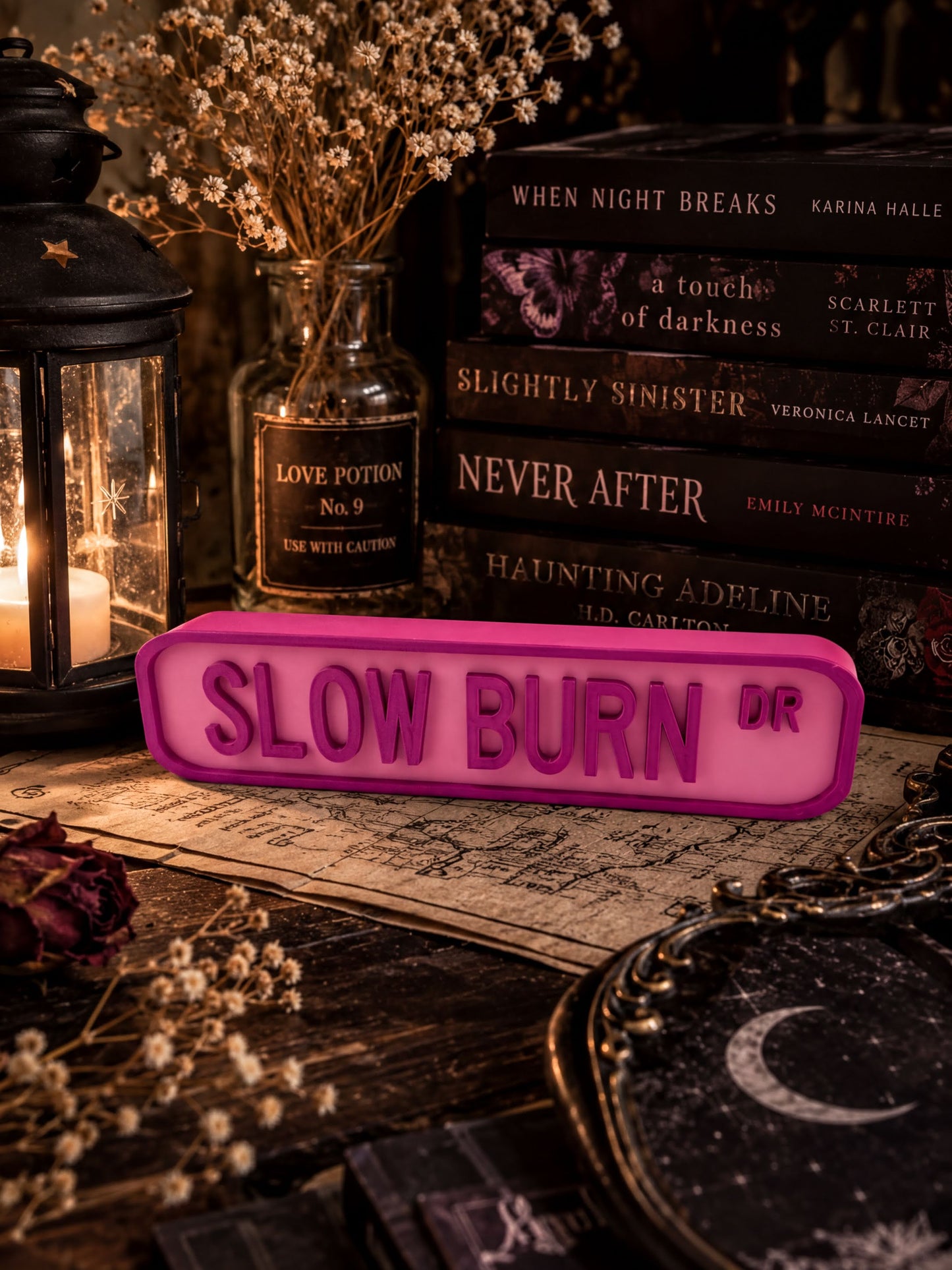 a collection of books, a pink sign, and some decorative elements arranged on a table.
