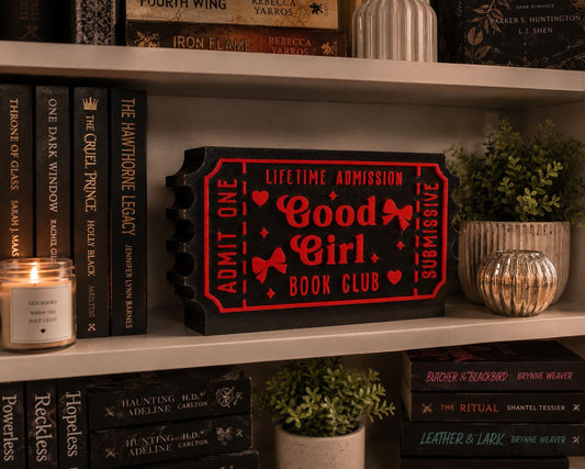 a bookshelf with various books, a candle, and decorative items such as a potted plant and a vase.