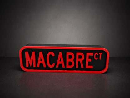 A red and black rectangular sign with the text "MACABRE" in bold red letters.