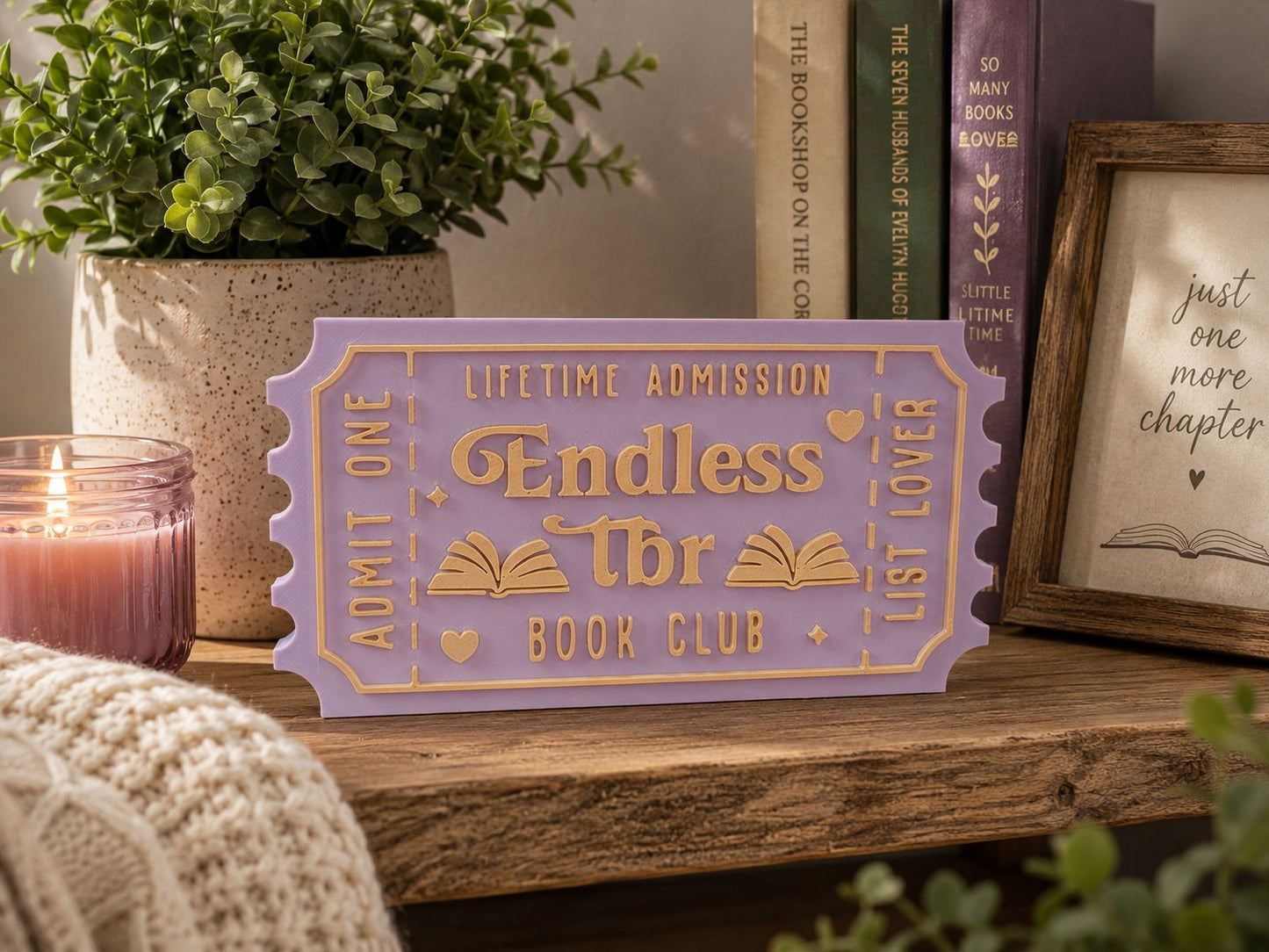a purple ticket-shaped sign with the text "Lifetime Admission" and "Endless" written on it, placed on a wooden surface. There are also some books and a candle in the background.