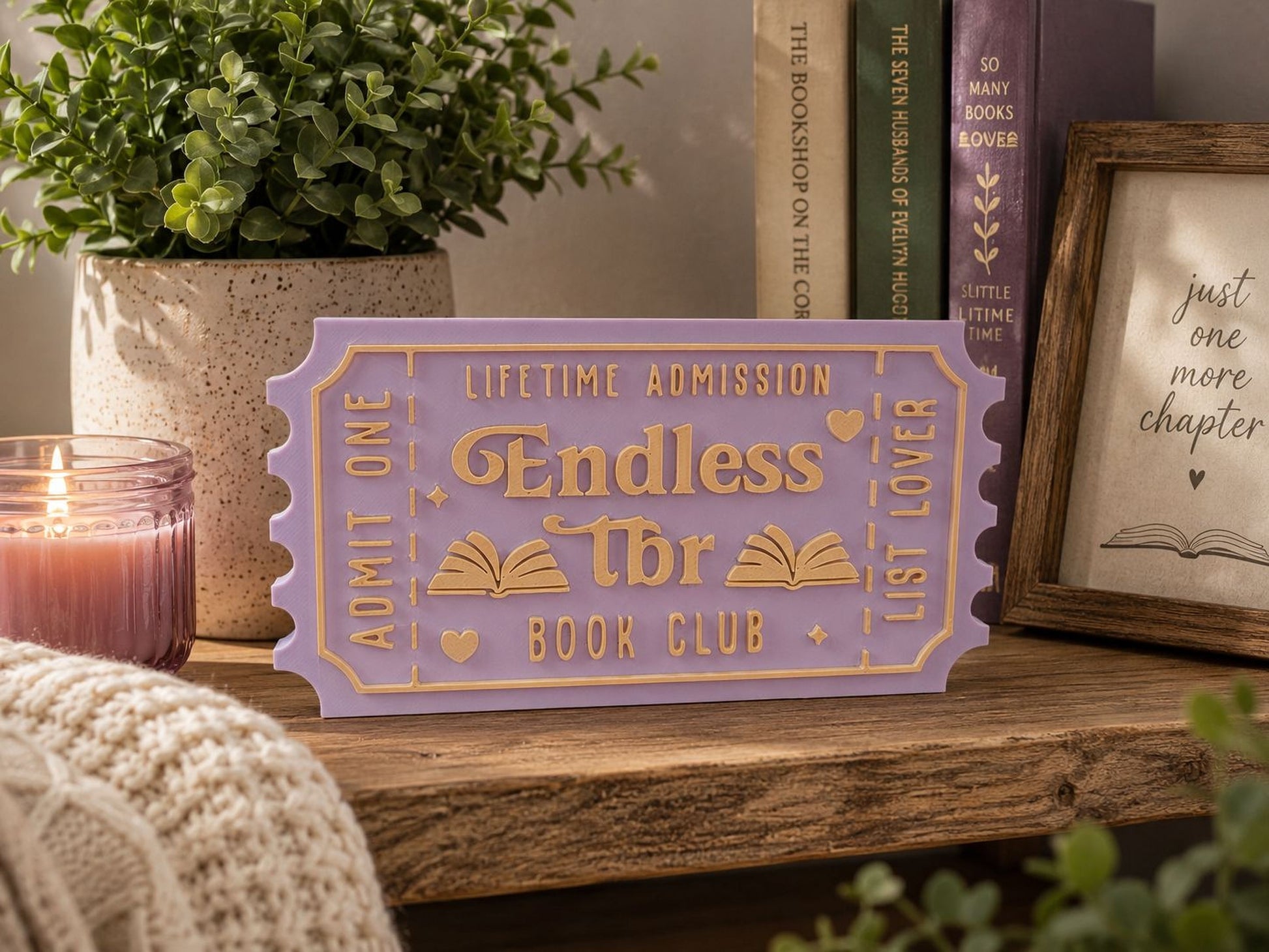 a purple ticket-shaped sign with the text "Lifetime Admission" and "Endless" written on it, placed on a wooden surface. There are also some books and a candle in the background.