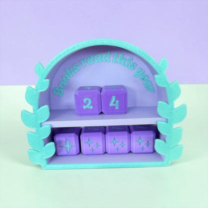 A purple and green shelf with purple cubes and leaves, displaying the text "Books read this year" and a number "24" on the cubes.