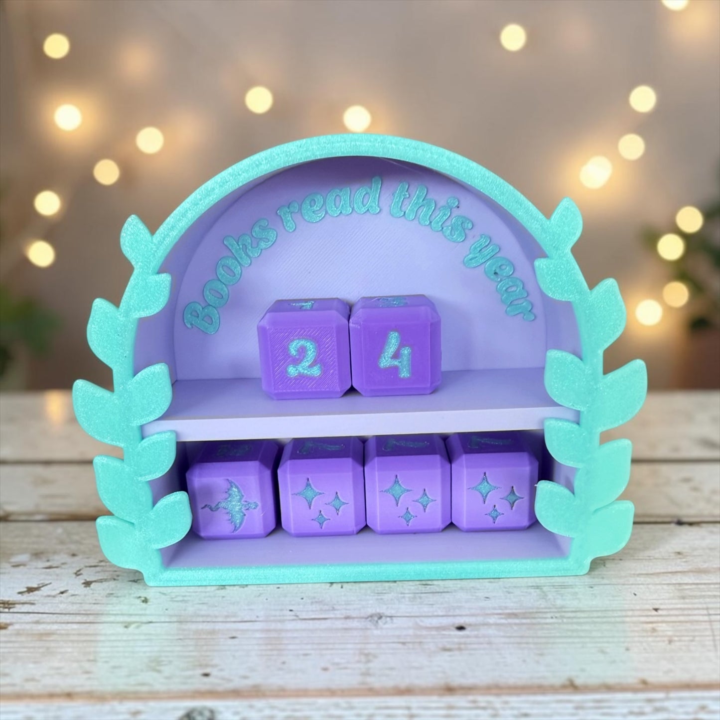 A purple and green shelf with purple cubes and a green leaf-shaped frame, displaying the text "Books read this year" and a number "24" on the cubes.