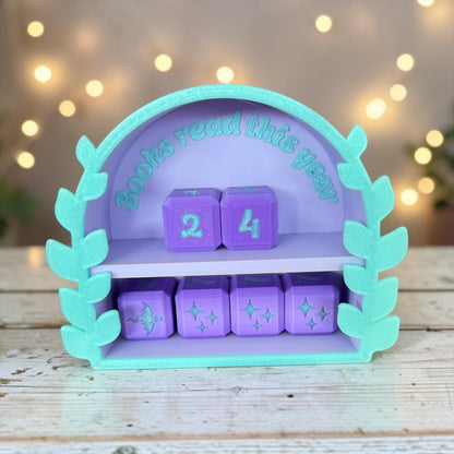 A purple and green shelf with purple cubes and a green leaf-shaped frame, displaying the text "Books read this year" and a number "24" on the cubes.