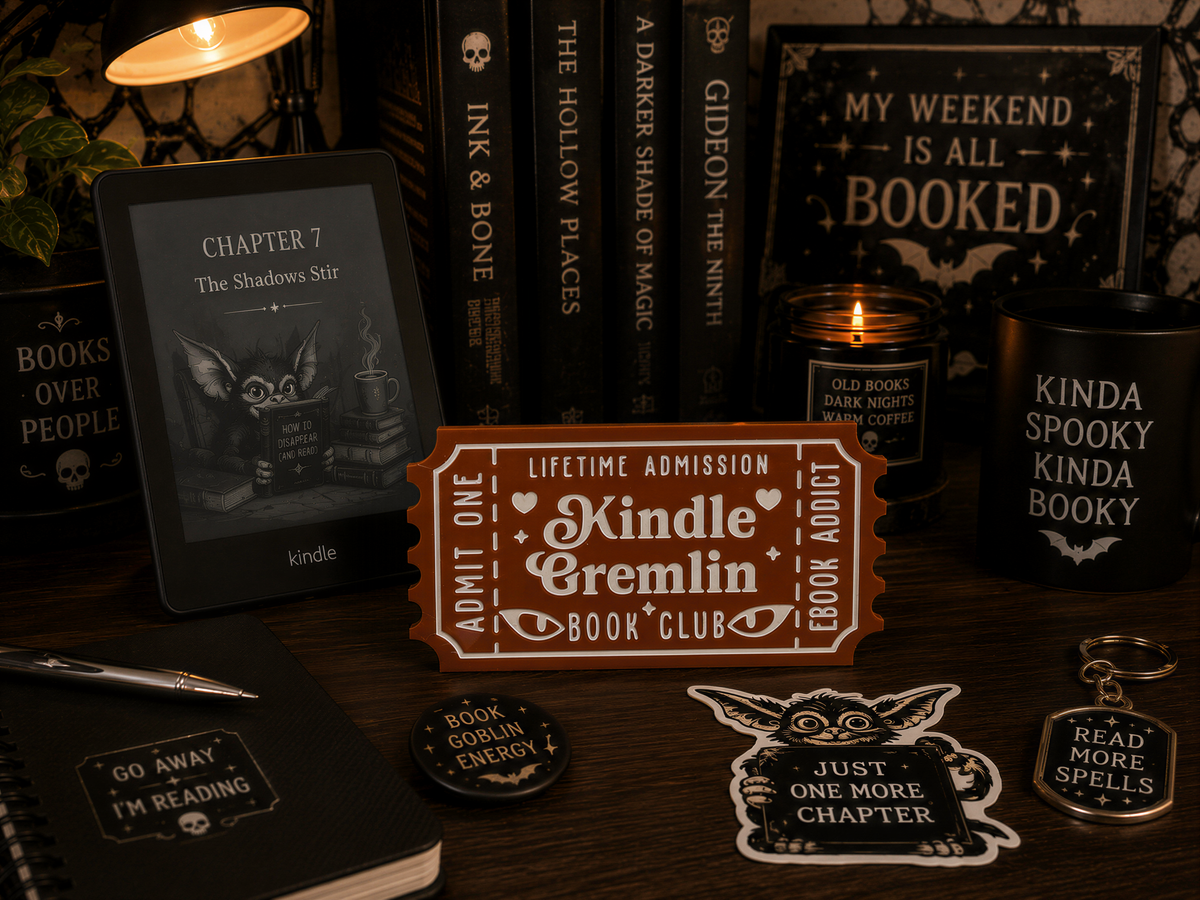 a collection of items related to the Kindle Book Club, including a Kindle e-reader, a book titled "The Shadows Stir", a candle, a mug, and various book-related items such as stickers and bookmarks.