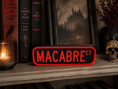 a shelf with various books, a skull, and a candle. The books are arranged in a row, and the shelf has a red and black sign that says "MACABRE".