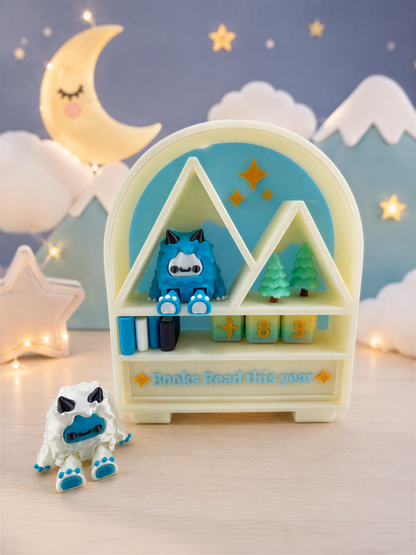 A toy shelf with a blue monster figurine and a white monster figurine, along with a sign that says "Books Read this year". The shelf is set against a night sky background with a crescent moon and stars.