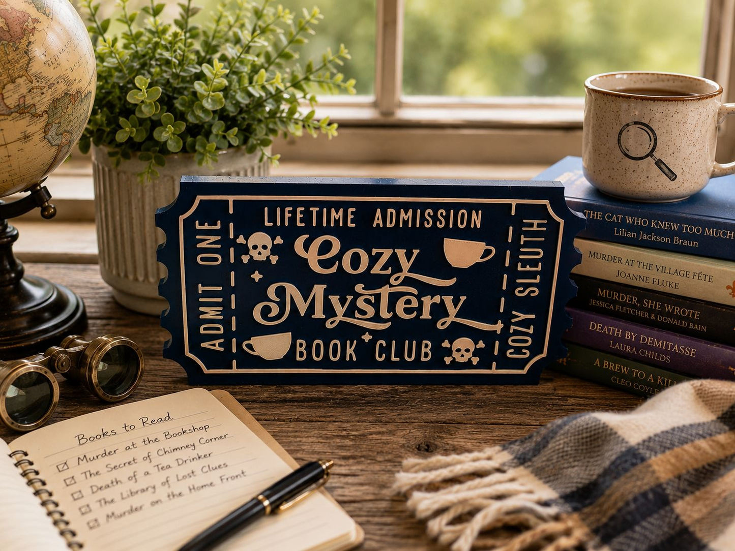 a desk with various items, including a book titled "The Cat Who Knew Too Much", a mug, a potted plant, a pair of glasses, a notebook, and a sign that says "Lifetime Admission Cozy Mystery Book Club".