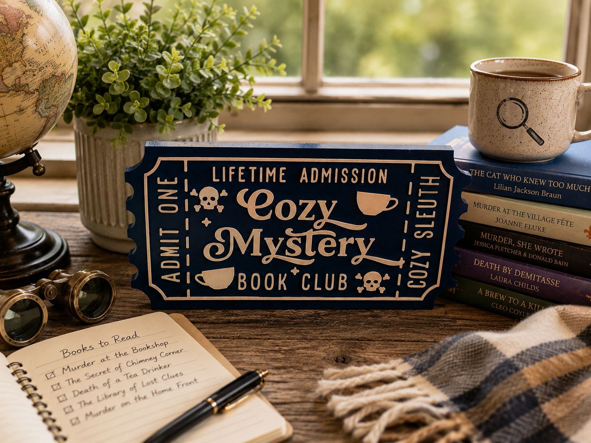 a desk with various items, including a book titled "The Cat Who Knew Too Much", a mug, a potted plant, a pair of glasses, a notebook, and a sign that says "Lifetime Admission Cozy Mystery Book Club".