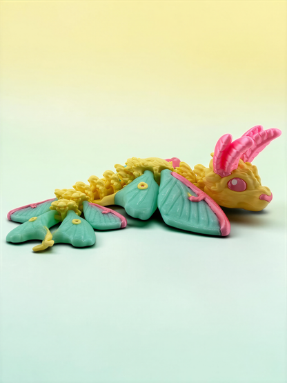 A colorful toy dragon with yellow and green body, pink horns, and green wings is sitting on a light green surface.