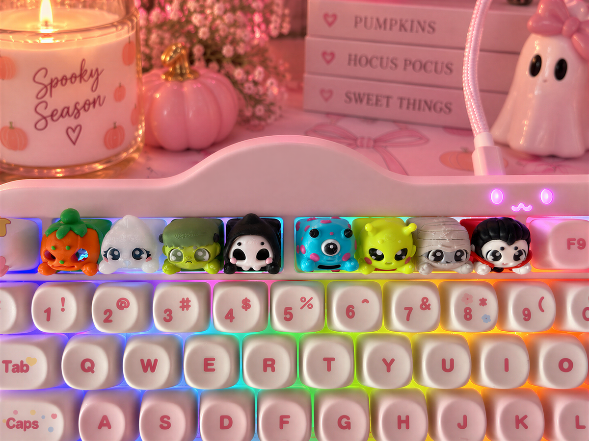A keyboard with colorful, cartoonish keycaps in the foreground, and a candle with a "Spooky Season" label in the background.