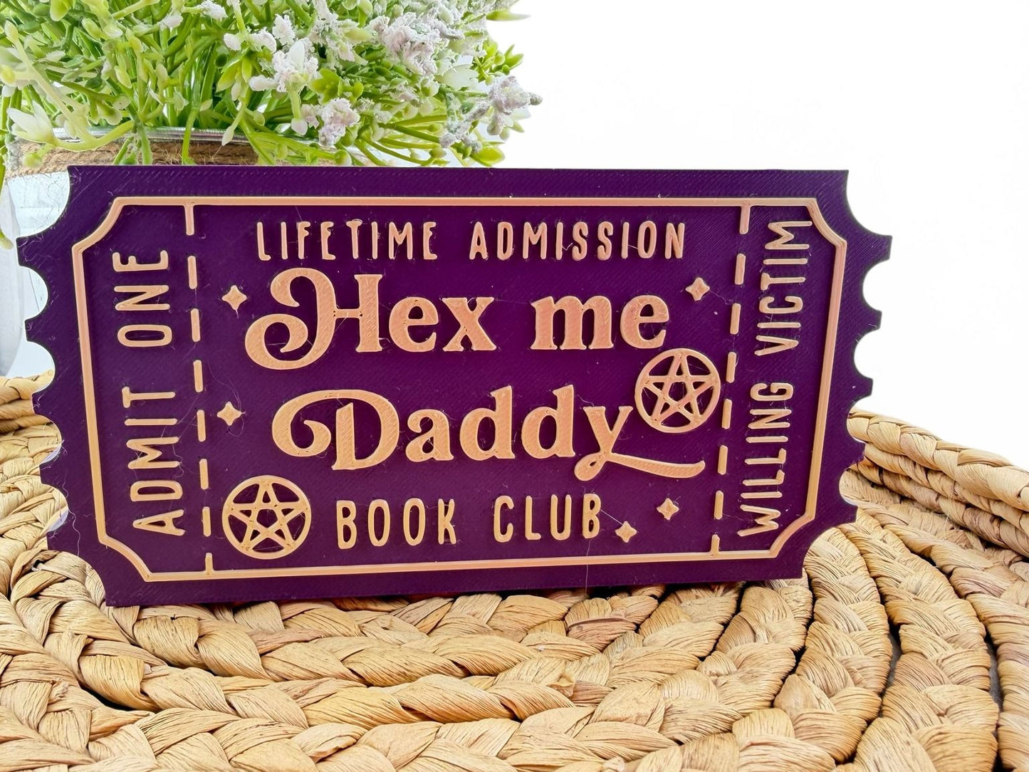 A purple ticket-shaped sign with gold text that says "Hex me Daddy Book Club" and " Lifetime Admission".