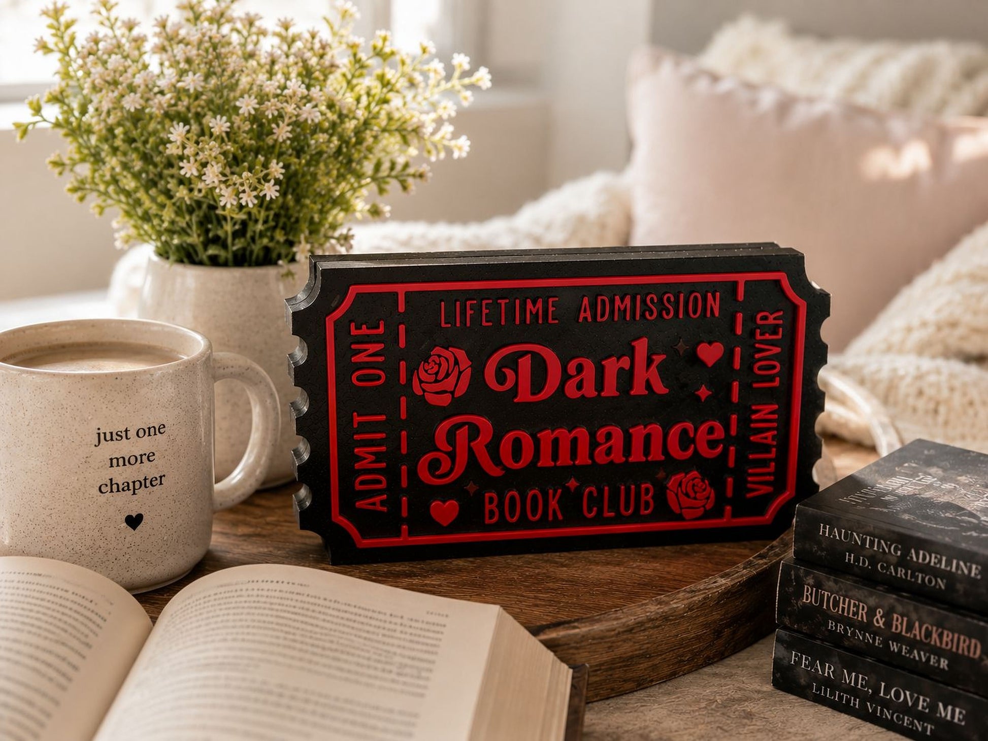a cozy scene with a book, a mug, and a ticket-shaped sign on a wooden table.