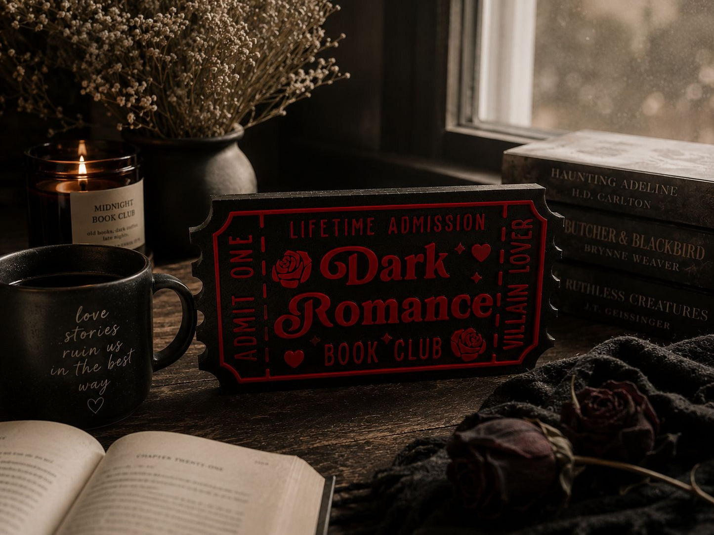 a cozy scene with a book, a mug, a candle, and a ticket for a book club. The book appears to be a romance novel, and the mug has the words "love stories run us on the best way" written on it. The candle and the ticket suggest a romantic atmosphere, and the presence of the book and the mug indicates that the setting is likely a reading or relaxation area.
