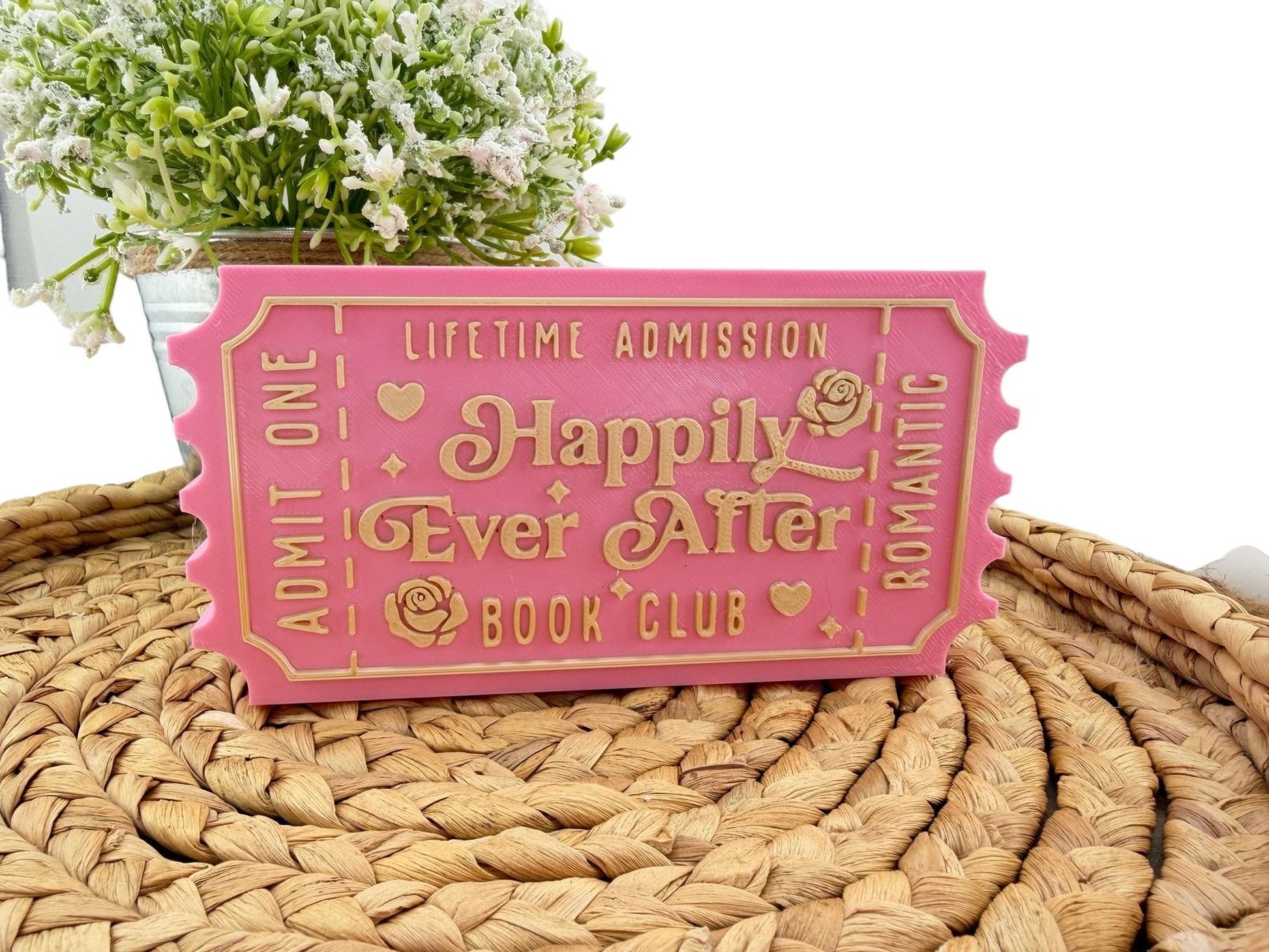 A pink ticket-shaped object with text on it, placed on a woven mat.