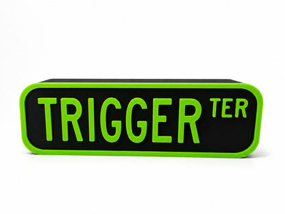 a black rectangular object with the word "TRIGGER" written in green letters on it.