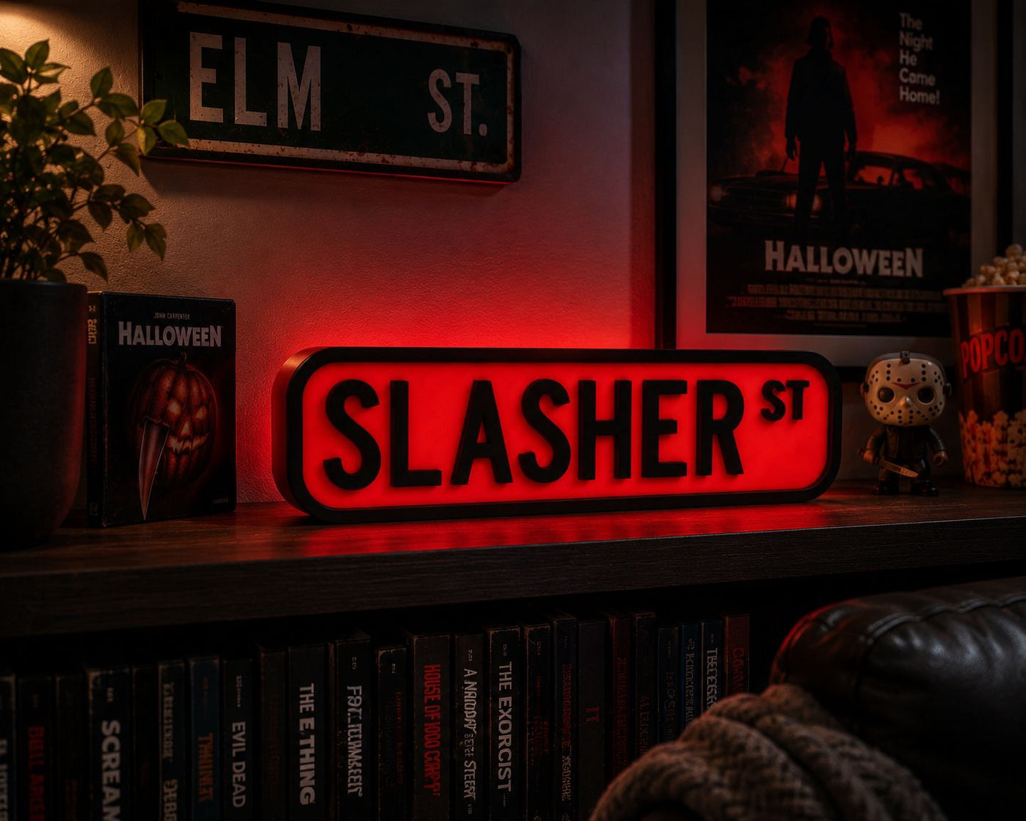 a shelf with Halloween-themed items, including a red sign that says "SLASHER ST" and a Halloween-themed book. There are also Halloween-themed decorations and a Halloween-themed popcorn container.