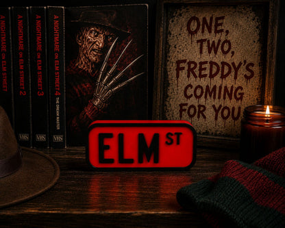 a collection of items related to the horror movie franchise, including a book, a poster, a sign, a hat, a candle, and a red sign with the word "ELM ST".