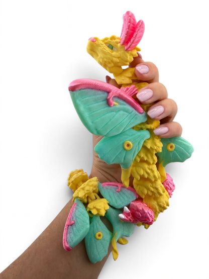 A hand holding a colorful, whimsical toy resembling a dragon or butterfly with vibrant green, pink, and yellow colors.
