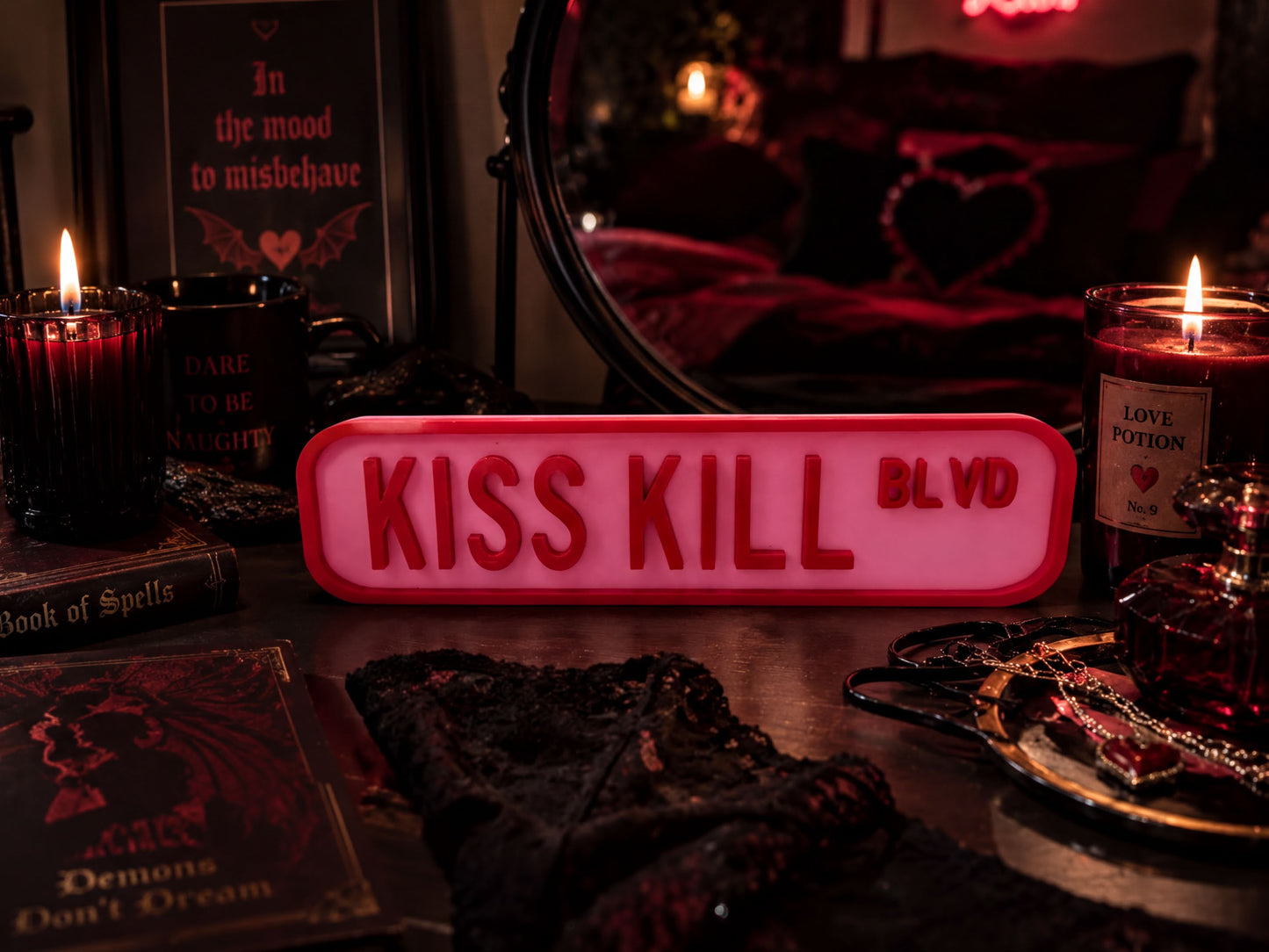 a dark and moody atmosphere with various objects, including a red sign that says "KISS KILL BLVD", a candle, a mirror, and some books.