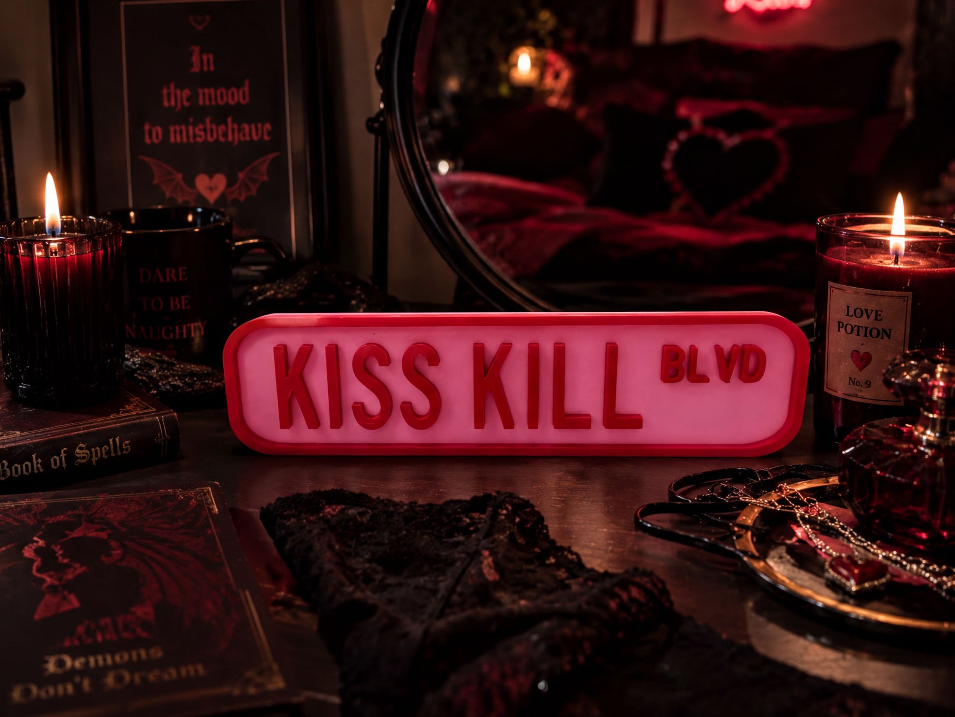 a dark and moody atmosphere with various objects, including a red sign that says "KISS KILL BLVD", a candle, a mirror, and some books.